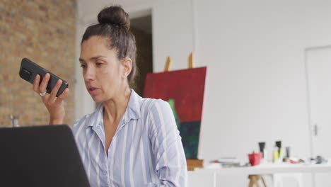 Video-De-Una-Feliz-Diseñadora-Birracial-Usando-Un-Teléfono-Inteligente-En-El-Estudio