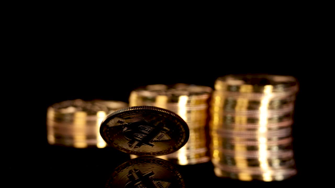 Gold digital coin spins on reflective surface, dramatic lighting, black background, slow camera movement