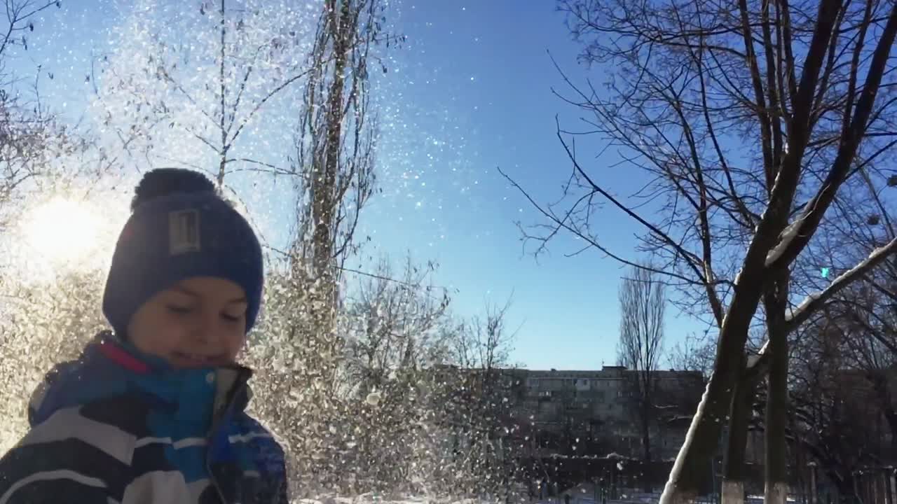 공중에 눈을 던지는 소년. 눈을 가지고 노는 어린 소년