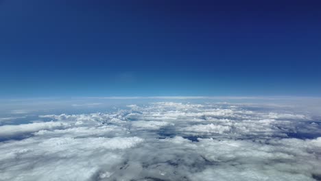 An immersive flight experience flying at the stratosphere at supersonic speed as seen by a jet pilot, with some broken clouds well bellow, and under a dramatic blue sky