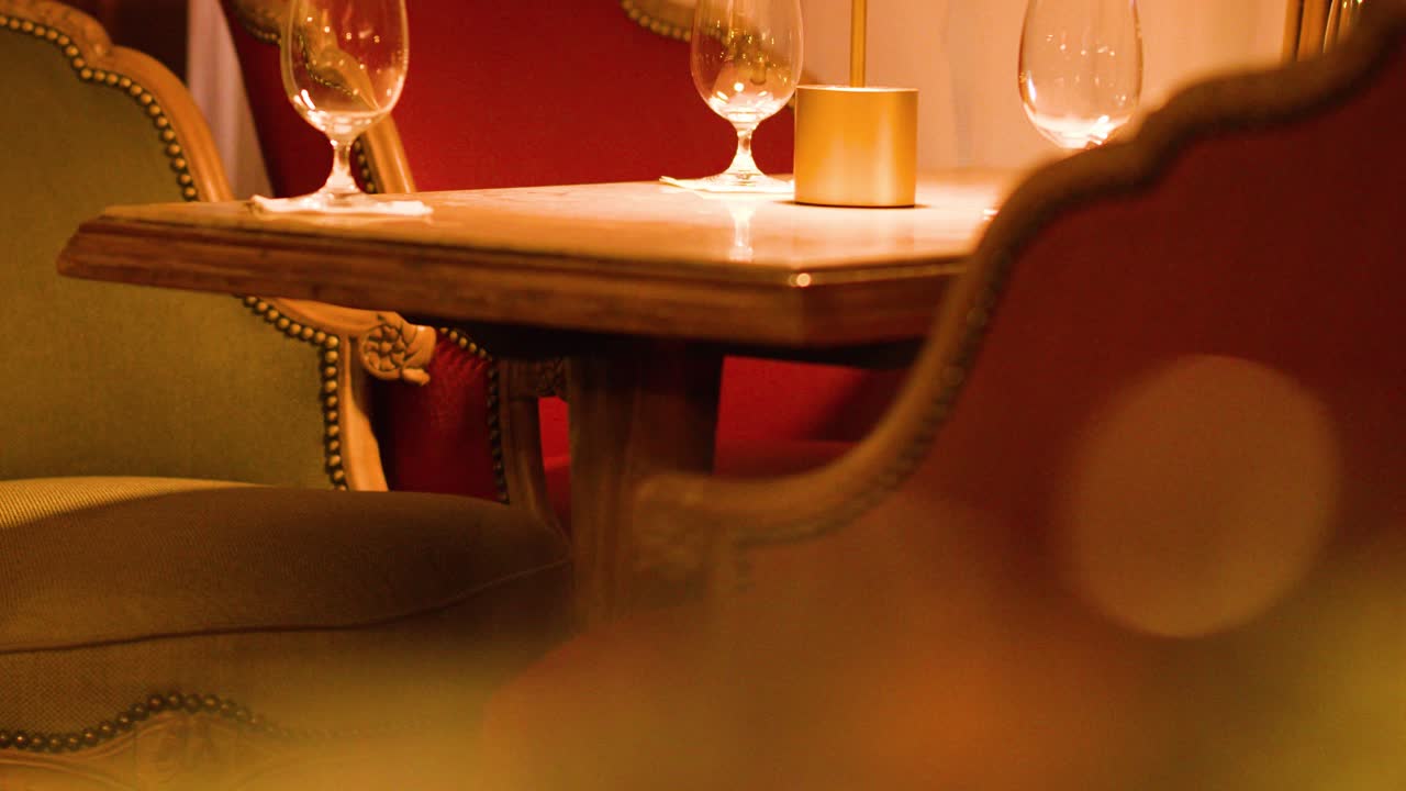 Luxurious restaurant table with wine glasses, cozy seating, and soft, intimate warm lighting throughout