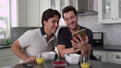 tilt shot of male couple using tablet computer at breakfast, shot on r3d