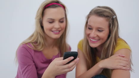 Female-friends-sending-a-text-message-together