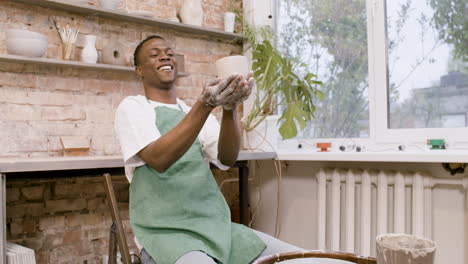 american clerk looking at a ceramic piece that he has modeled on the potter wheel