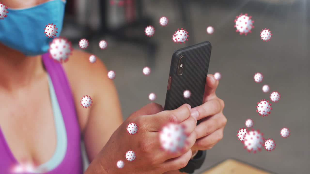 múltiples células de covid-19 flotando contra una mujer caucásica en forma que usa una máscara usando un teléfono inteligente