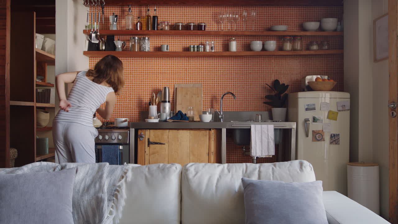 happy young woman dancing in kitchen celebrating successful lifestyle enjoying cheerful victory dance celebration at home on weekend