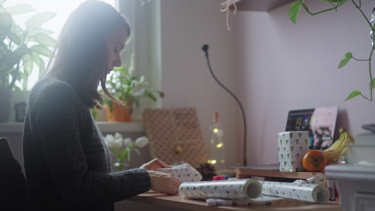 Young beautiful white girl packing gift items with white decorative paper for celebrating an event