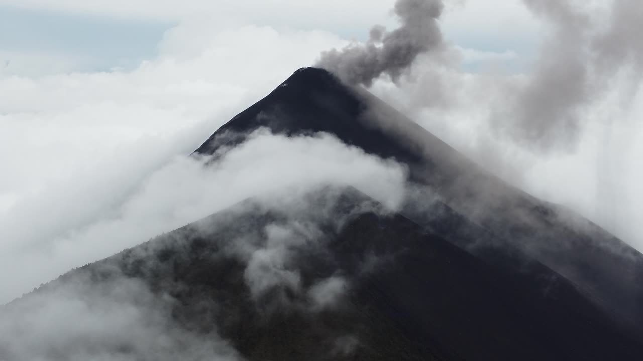 video de drones de un volcán activo medio cubierto por nubes en antigua, guatemala