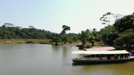 Video-Panorámico-Aéreo-De-4k-Con-Personas-Abordando-Un-Bote-En-Las-Costas-Tropicales-De-La-Laguna-De-Los-Milagros-En-Tingo-Maria,-Ciudad-Llamada-Puerta-A-La-Amazonía,-En-Perú