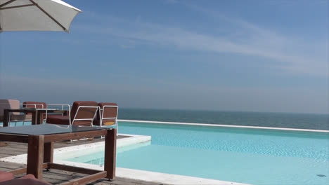 chair and umbrella with swimming pool and sea beach background