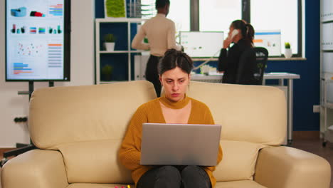 concentrated manager reading mails typing on laptop sitting on couch