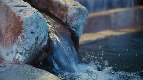 Natural-hot-spring-water-flowing-into-stone-bath-at-Japanese-onsen