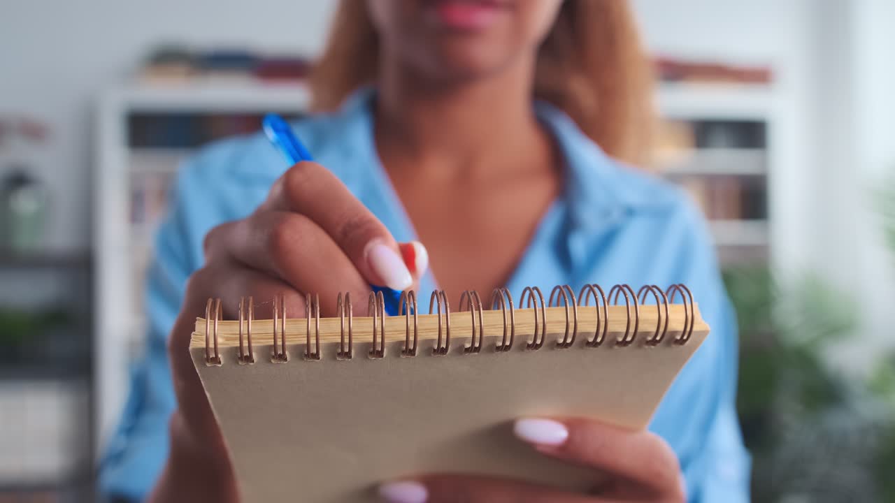 Close up hand african american woman with pen making notes in notepad