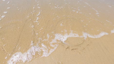 palabra no dibujada en la arena de la playa cubierta por olas marinas