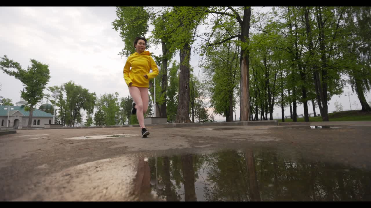 Woman jumping in a puddle in a park