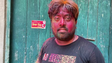 indian beard man in black dress with full face and hair covered with color powder opening money heist mask