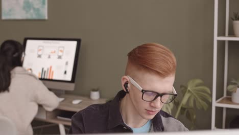 young ginger man working on computer in office