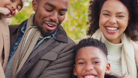 portrait of smiling family with parents with children on walk through autumn countryside together looking at camera - shot in slow motion