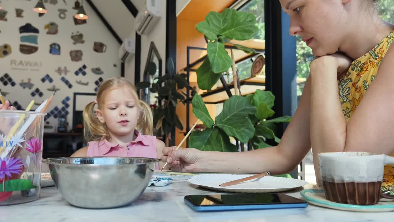 madre e hija pintando cerámica en un café
