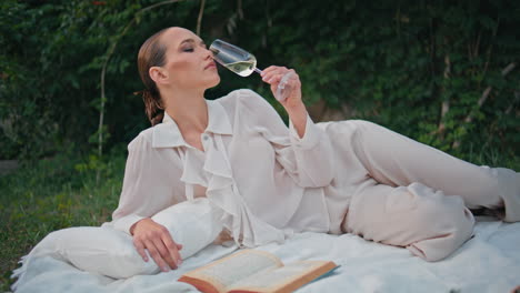 chic woman relaxing wine on picnic blanket summer weekend. model drinking tasty