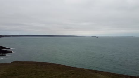 Panning-Aerial-of-Pembrokshire-Coastline-with-Calm-Sea-on-Cloudy-Day-UK-4K