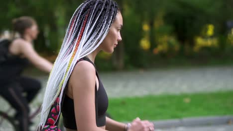 cheerful woman walking to the work or training by the park, uses her smartwatch, tapping on it, checking time. positive mood