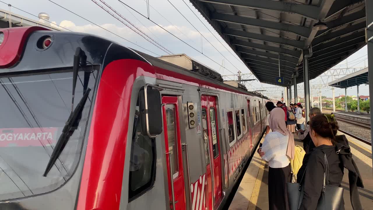 People waiting for and boarding a commuter train at a station in Indonesia