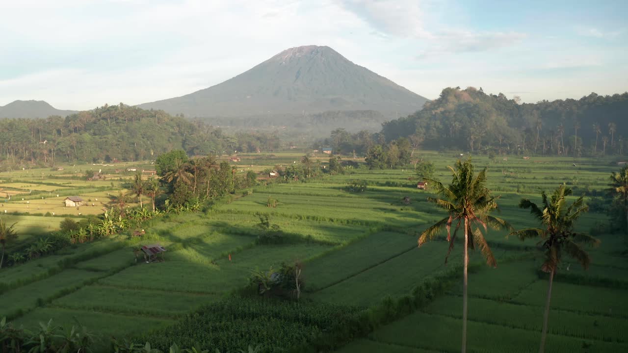 impresionante vista del volcán mount agung rodeado de verdes campos de arroz y palmeras en bali, indonesia