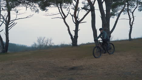 atleta ciclista masculino montando una bicicleta de montaña en el campo