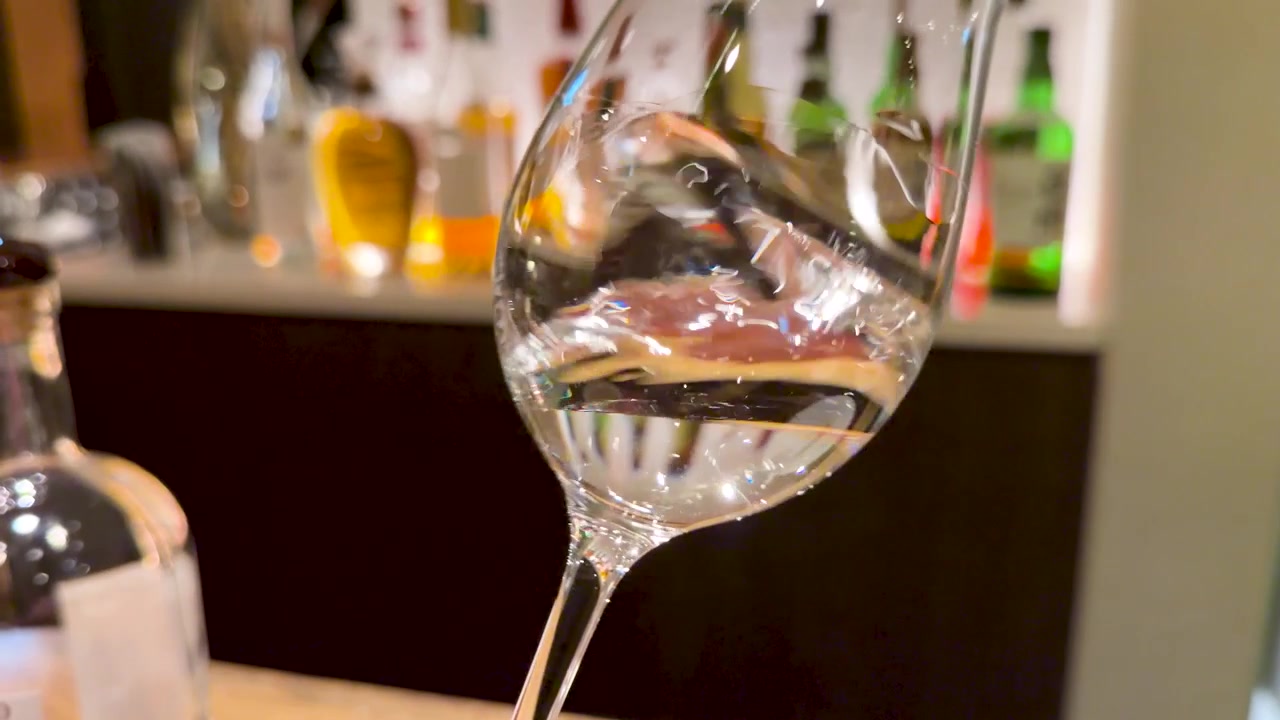 Un primo piano di sake giapponese trasparente che vortica all'interno di un bicchiere in un bar.