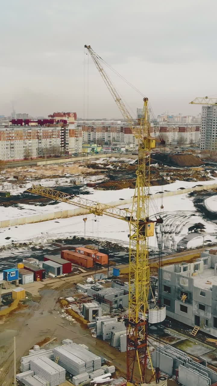 yellow building cranes located in row on construction site against residential district and blue sky aerial view