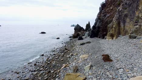 Gentle-ocean-waves-brush-against-rocky-pebble-shores-of-Catalina-island,-aerial-dolly