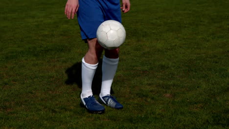 football player in blue controlling the ball on pitch
