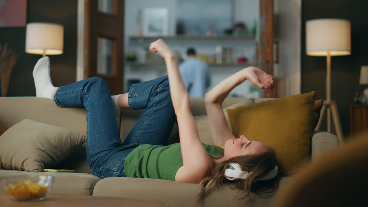 auriculares hipster música relajante colocando sofá acogedor plano. mujer feliz moviendo las manos