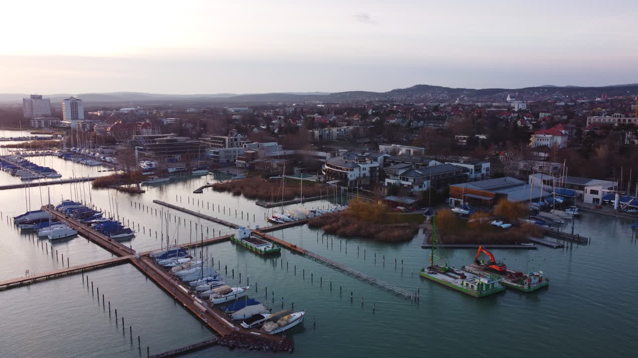Wide drone view of Balatonfured harbor with island dock and boats under bright cloudy sky
