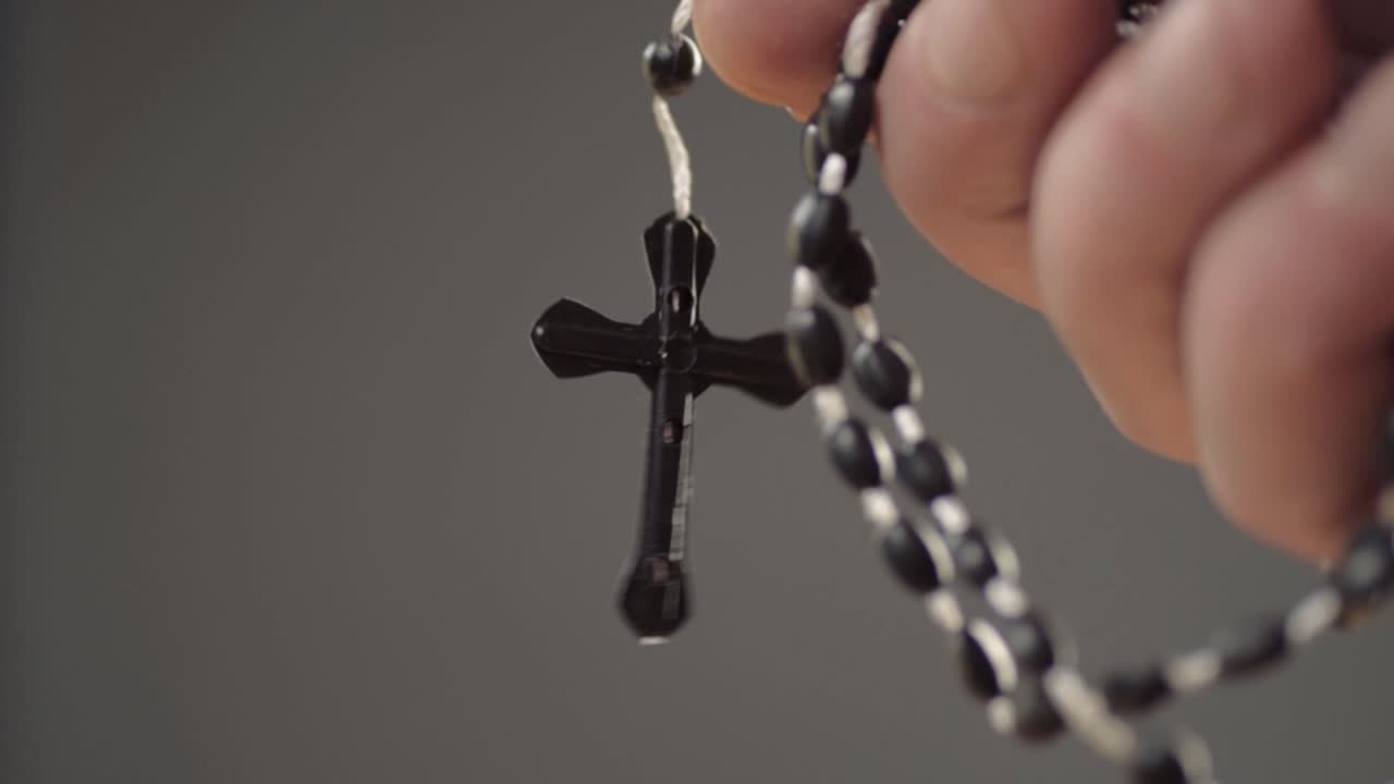 Mãos segurando um terço com crucifixo em close-up