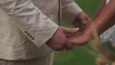 The-groom-lovingly-clasps-the-bride's-hands-at-her-wedding