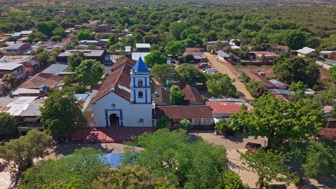 Uma panorâmica suave da direita para a esquerda com drone revela a Capilla Santa Bárbara, igreja icônica azul e branca em Villavieja, Colômbia. A foto mostra as ruas ao redor e o isolamento da cidade do deserto de Tatacoa