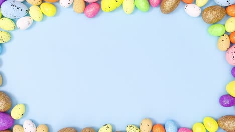 colorful easter eggs make copy space frame on pastel blue background. stop motion