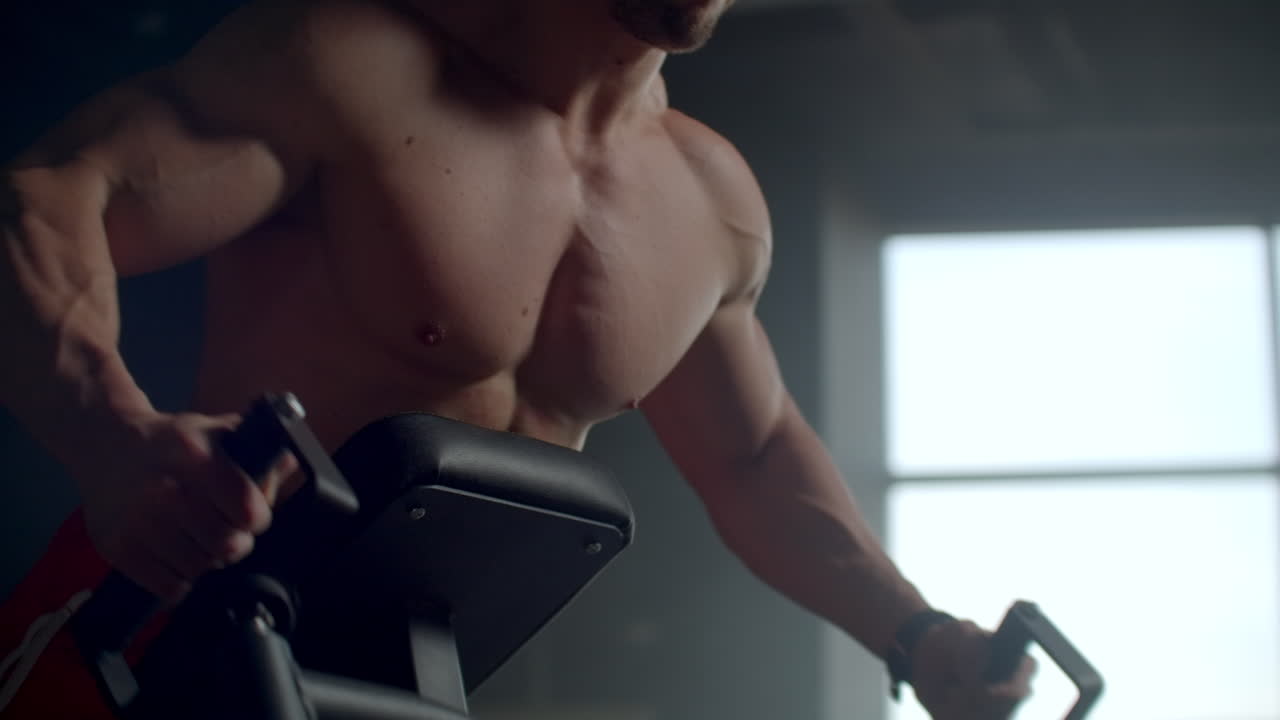 un hombre en un club de fitness tira de una barra en una inclinación realizando ejercicios para los músculos de la columna vertebral.