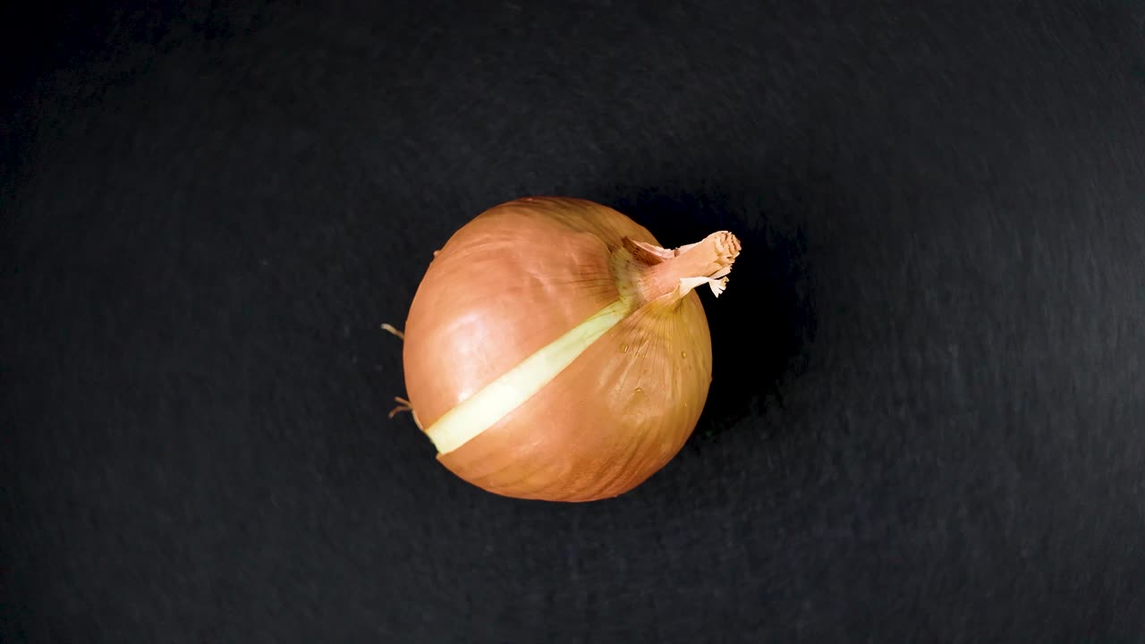 Rotating onion on a black background, showcasing its smooth texture and shape