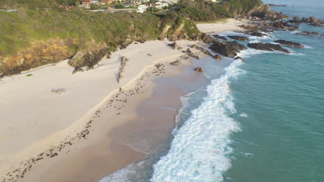 waves sea level retracing from rocky australian beach, backwards aerial reveal