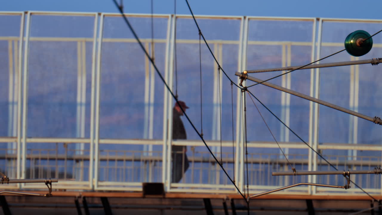 Distant view of a man walking on a bridge, with cars moving near him