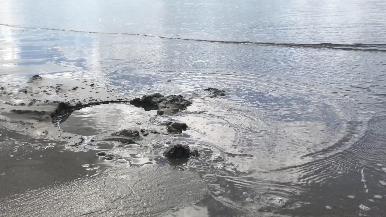 해변의 모래 구멍으로 부드럽게 흐르는 바닷물