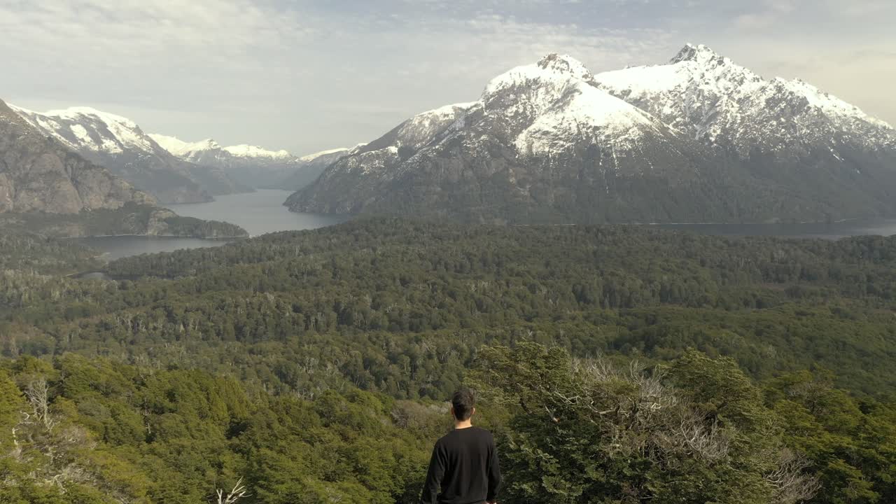 toma aérea de un hombre irreconocible llegando a un mirador de lagos y montañas patagónicos