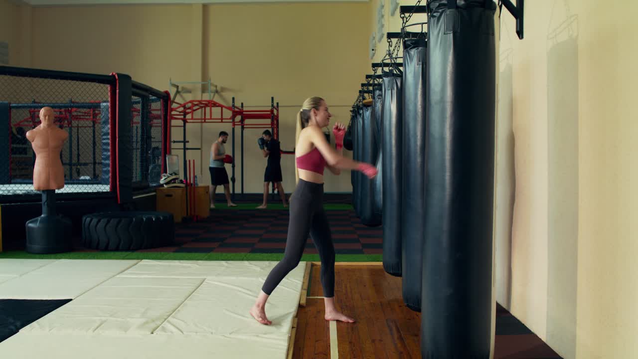 Pessoas treinando em uma academia com sacos de pancada e equipamentos de artes marciais