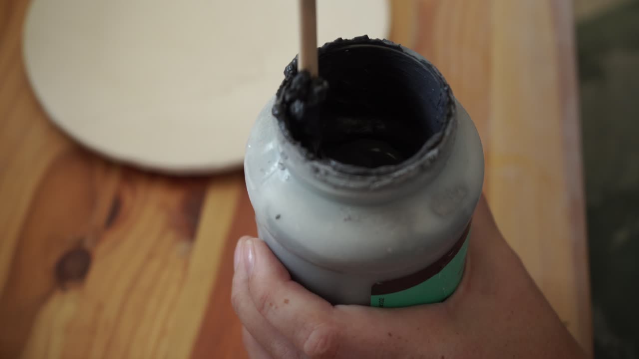 primer plano del artista mezclando pintura en una olla