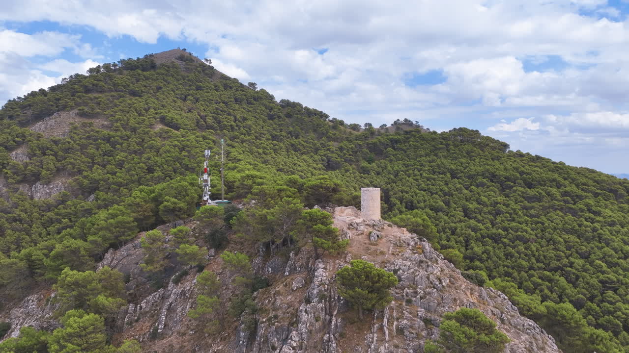 Aerial close up to the medieval El Canuto watchtower on the steep forested peak