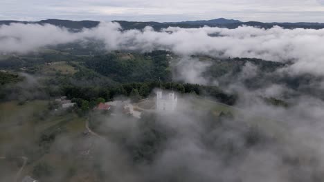 hermosa vista de la iglesia en la cima de la colina en la niebla