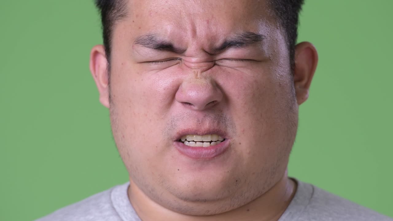 초록색 배경에 젊은 잘생긴 과체중 아시아인